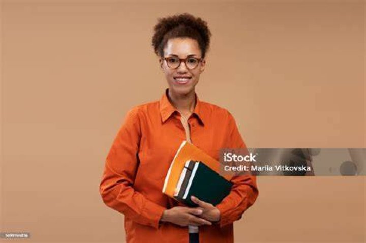 A tutor wearing glasses is with young student reading a book together