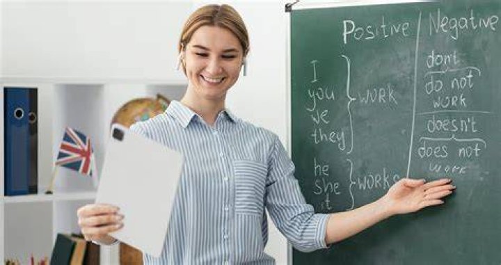 An English teacher holding a notebook while in a classroom