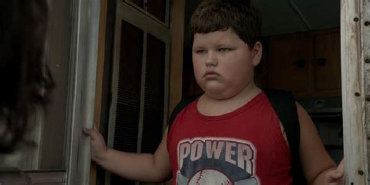 Chuckie from Shameless stands in the doorway wearing a red singlet with the word 'Power' on it