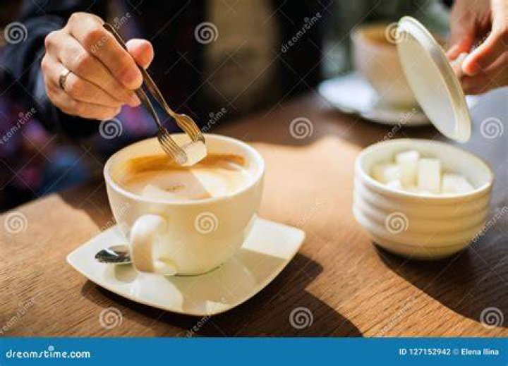 Man adding sugar to coffee mug at restaurant table man adding sugar to coffee mug at restaurant table