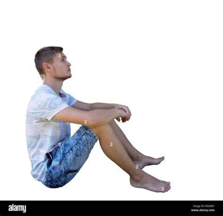 person sitting on ground with red suitcase in front of them