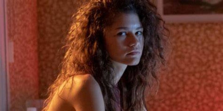 Rue sits on a bed in Euphoria