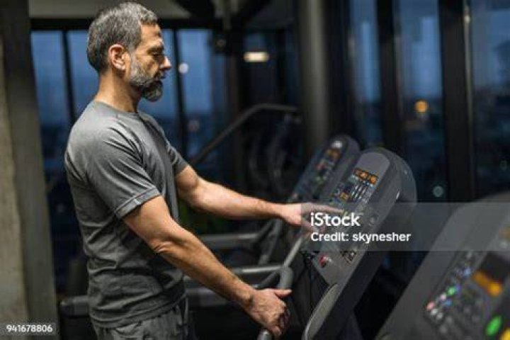 Senior man adjusting speed on treadmill at rehab senior man adjusting speed on treadmill at rehab