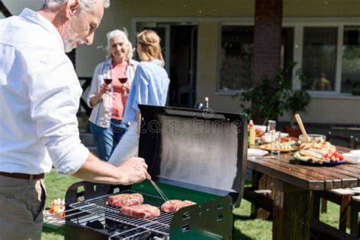Senior man making barbecue for his family's lunch on a terrace. senior man making barbecue for his family's lunch on a terrace
