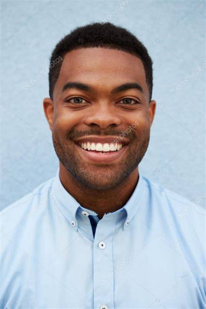 Young african american man with a hearty smile hold smartphone in his hands, typing message, chatting with friends in social networks, playing online game, isolated against grey wall young african american man with a hearty smile hold smartphone in his hands, typing message, chatting with friends in social networks, playing online game, isolated against grey wall